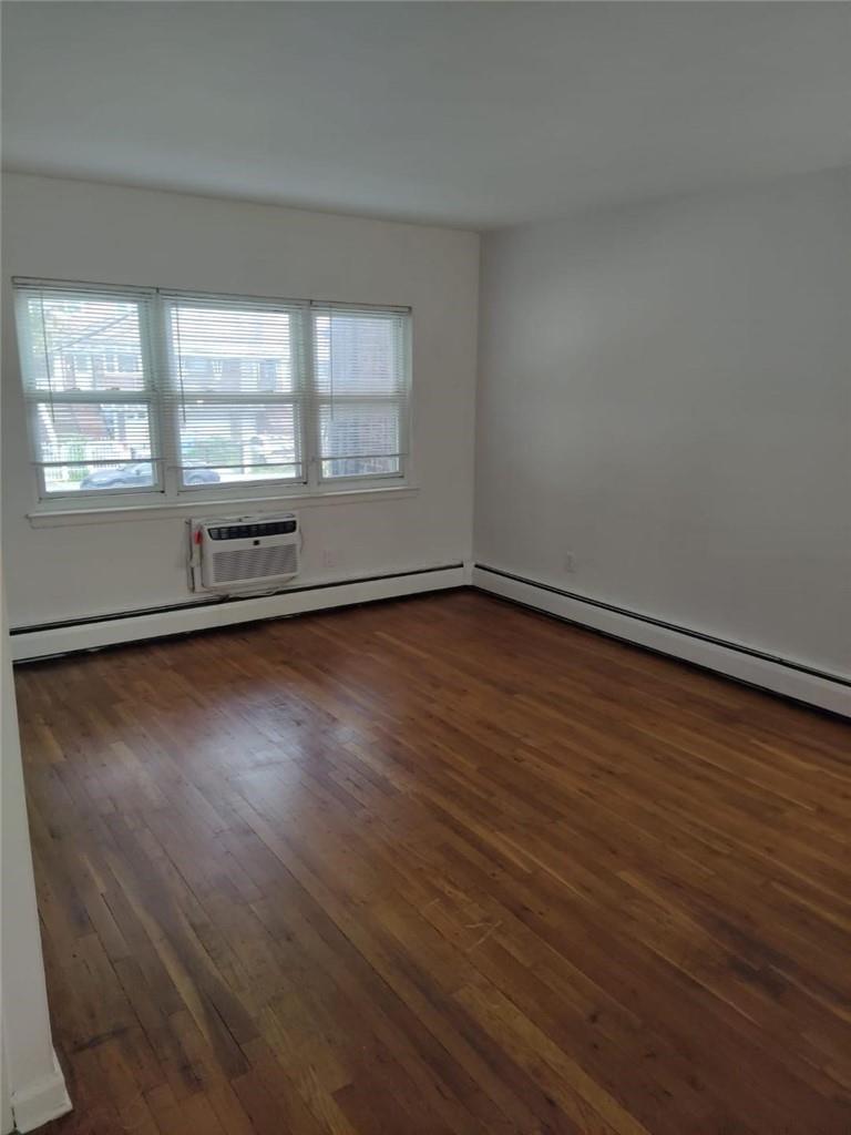 Unfurnished room featuring dark hardwood / wood-style flooring and a wall unit AC