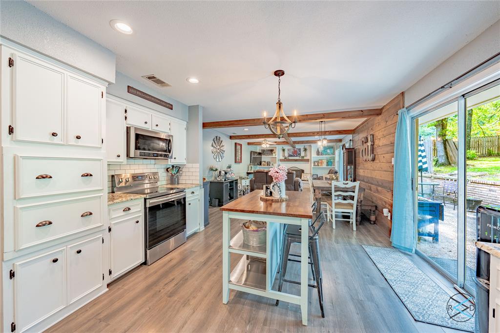 a open kitchen with stainless steel appliances a dining table chairs stove and white cabinets