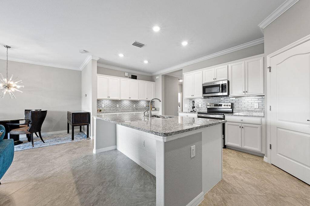 a kitchen with kitchen island granite countertop a sink counter top space appliances and cabinets