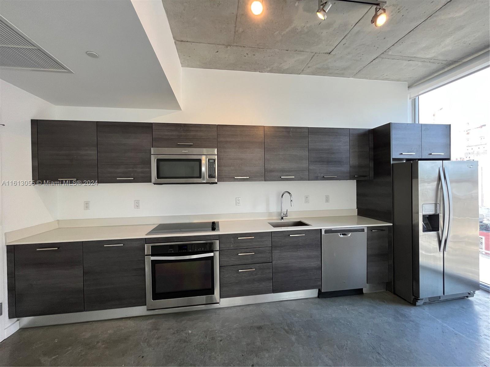 a kitchen with stainless steel appliances a stove a microwave and a sink