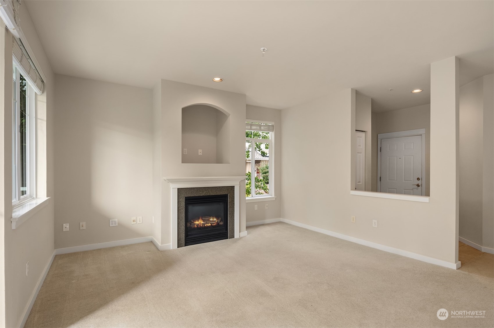 an empty room with windows and fireplace