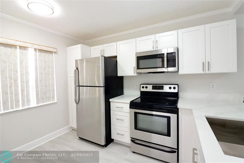 a kitchen with granite countertop white cabinets and stainless steel appliances