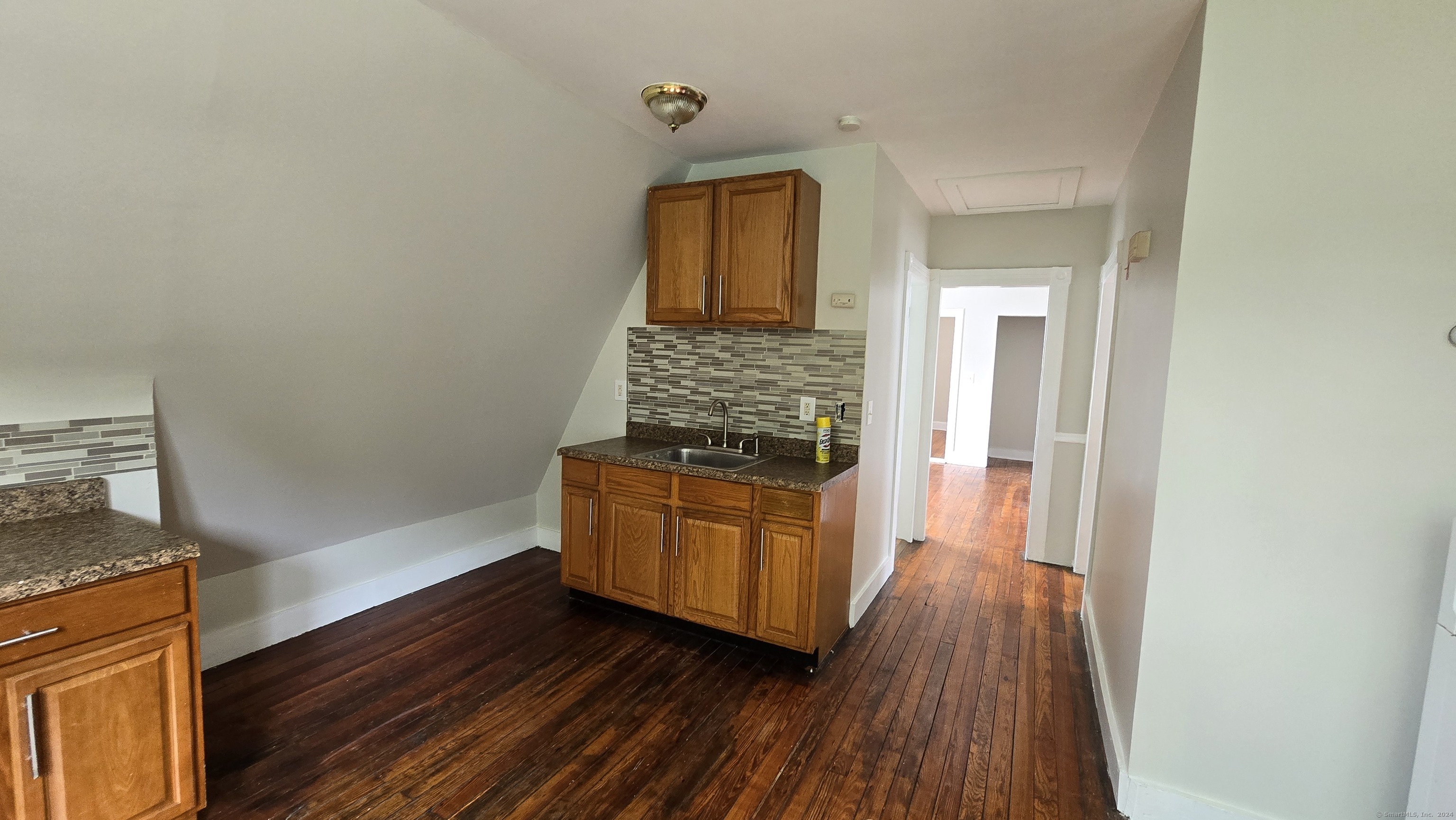 a hallway with wooden floor and cabinet