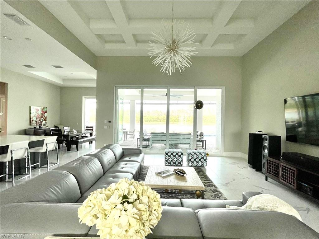 Living room featuring coffered ceiling, beamed ceiling, and a chandelier