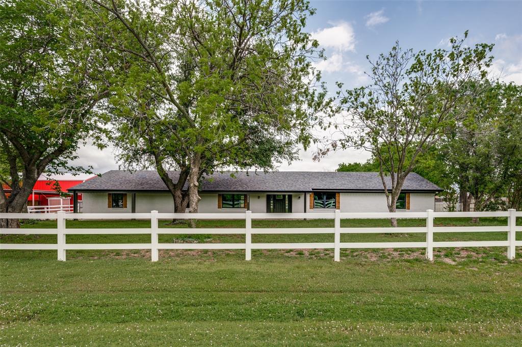 a white house with a big yard and large trees