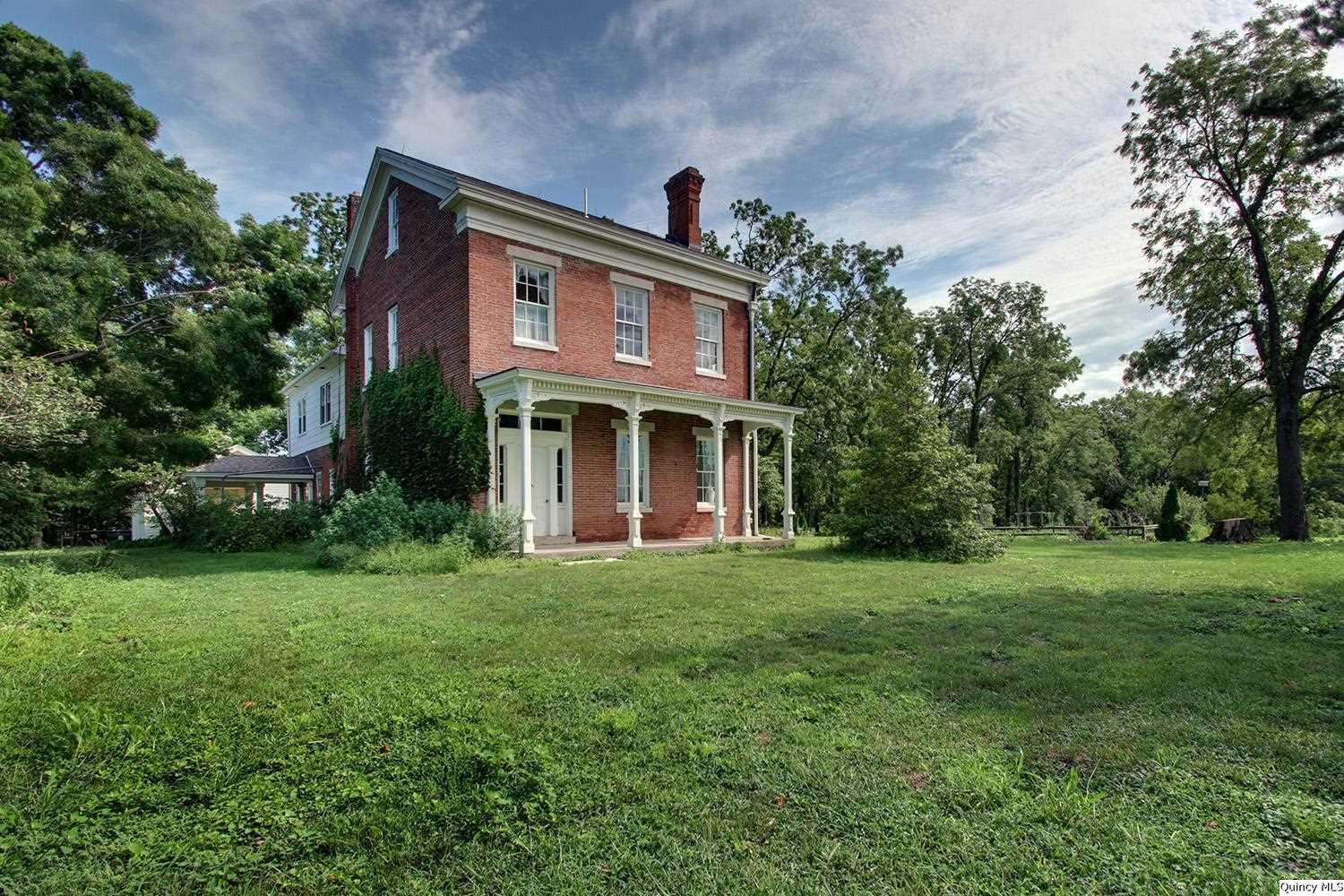 a view of a brick house with a big yard and large trees