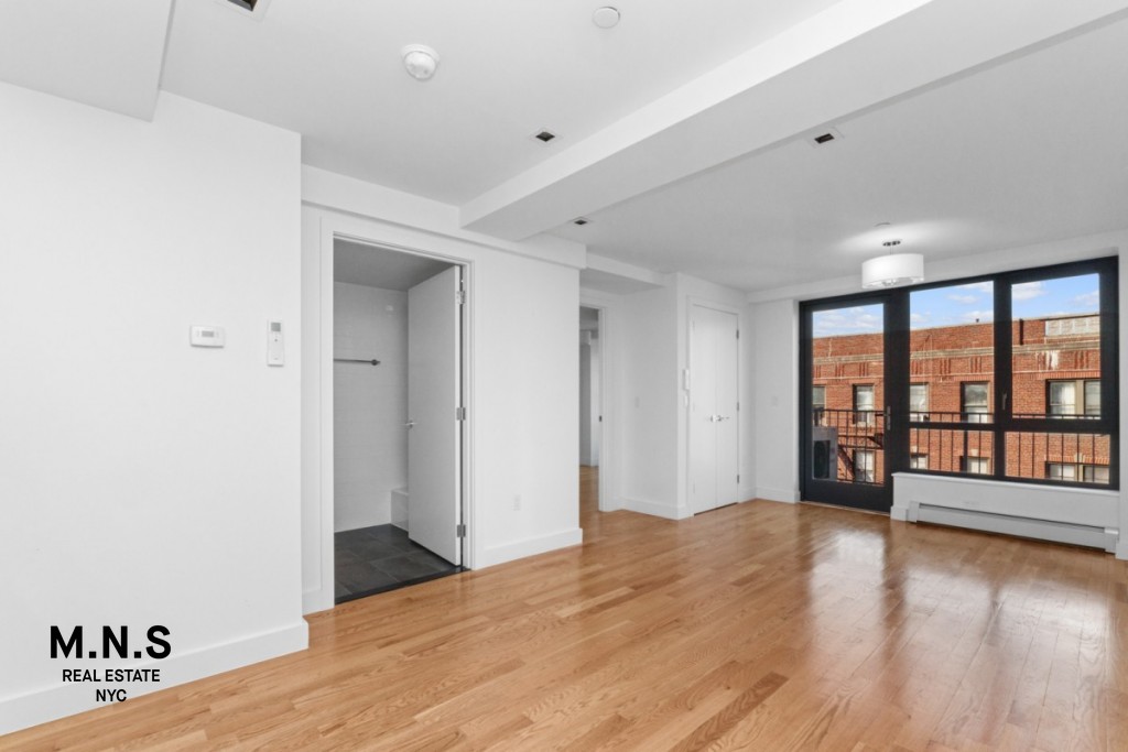 a view of an empty room with window and wooden floor