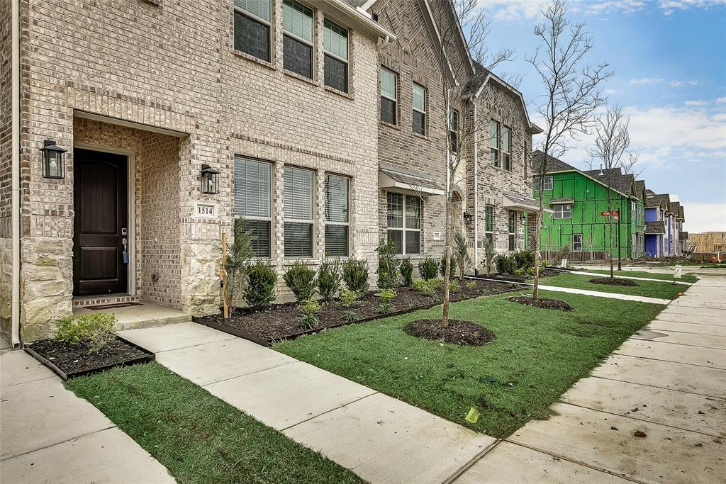 a view of a brick house with a yard garden and large tree