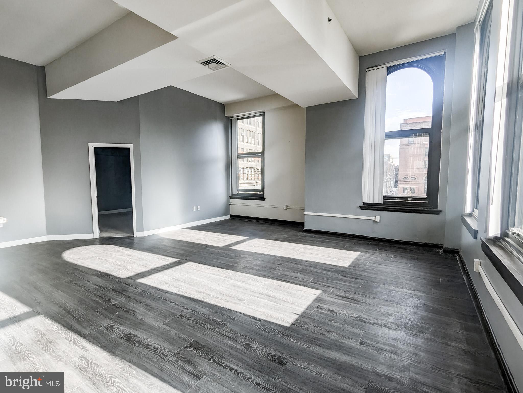 an empty room with wooden floor and windows