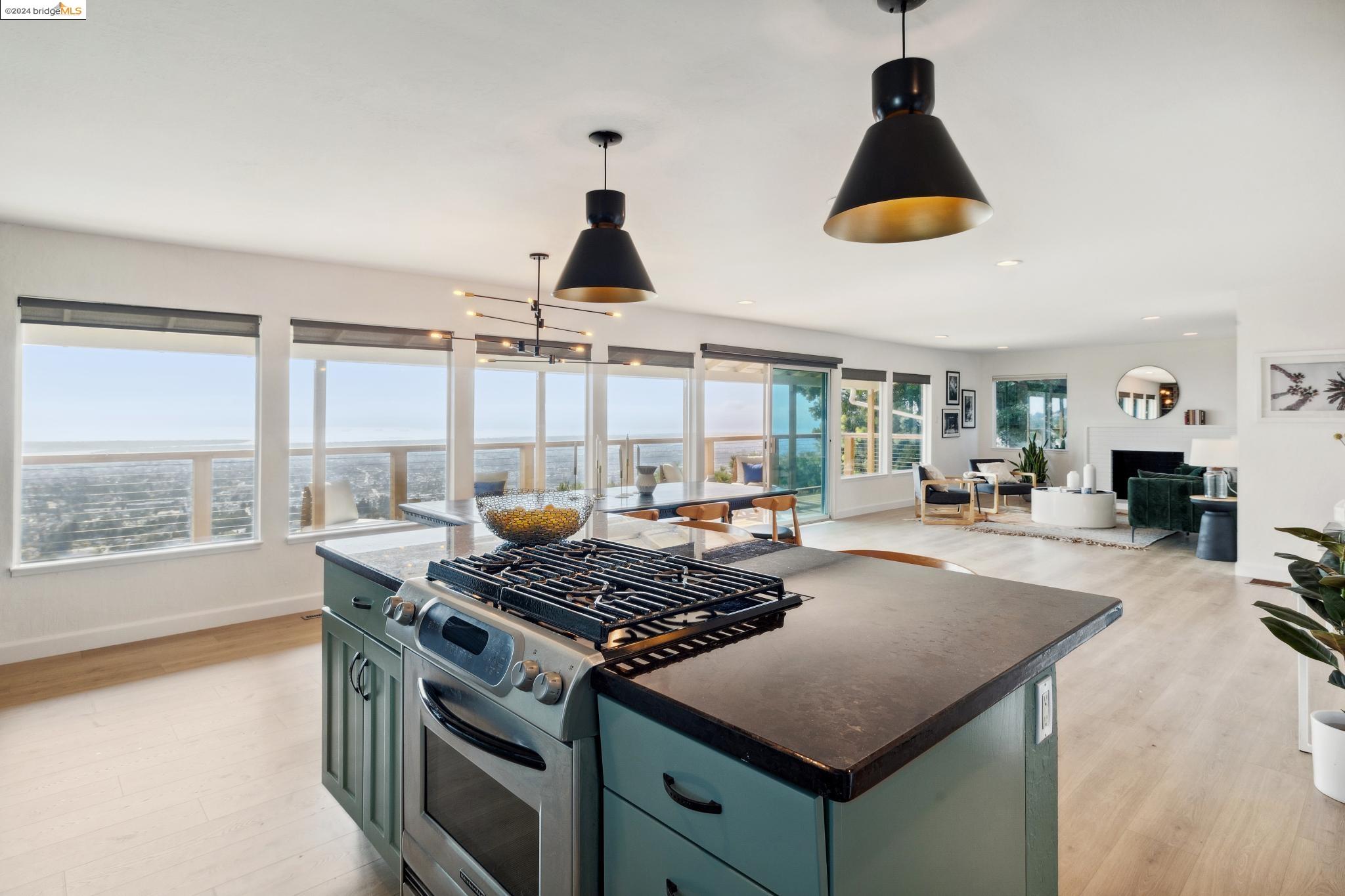 a kitchen with stainless steel appliances a stove a chimney a sink and a living room view