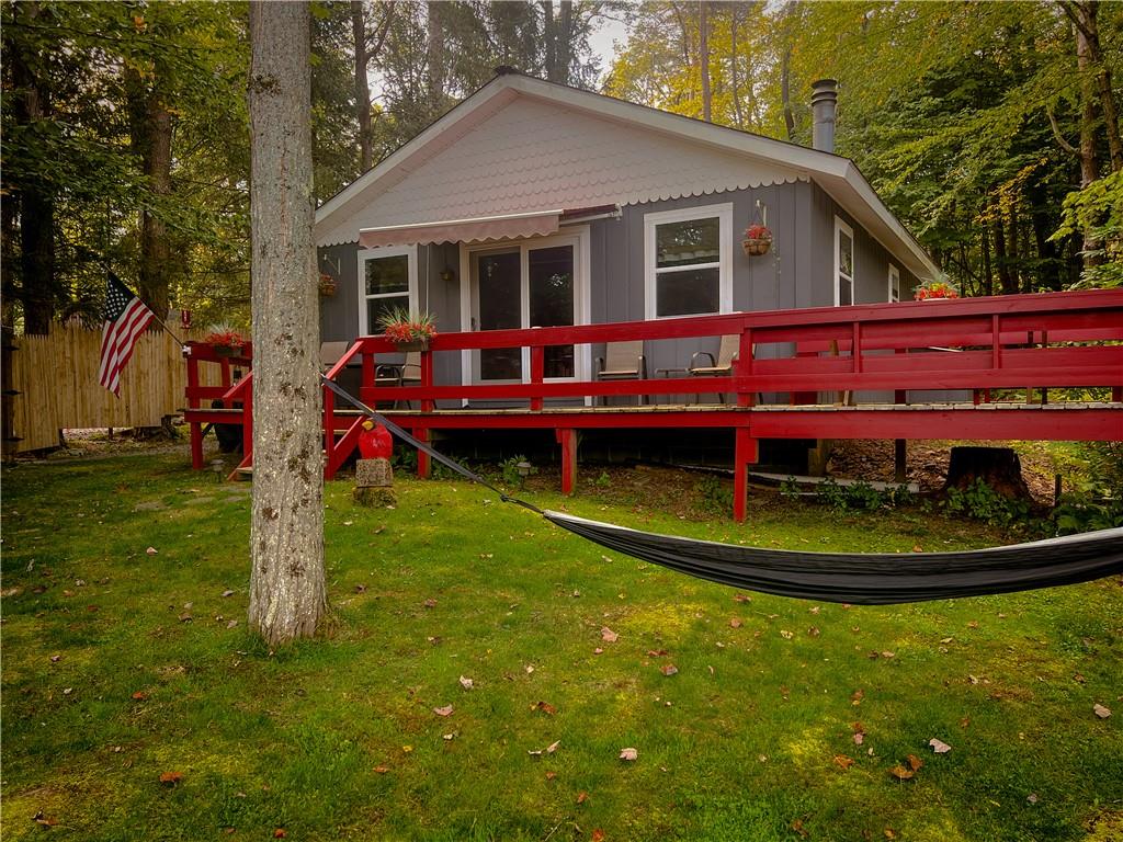 Rear view of house featuring a lawn and a deck