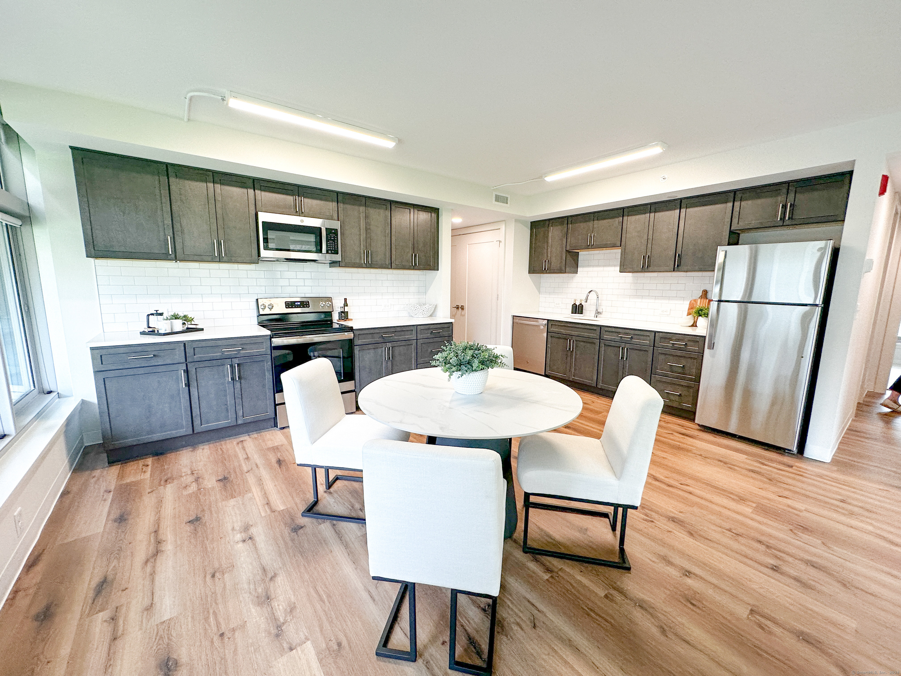 a kitchen with stainless steel appliances a dining table chairs microwave and sink