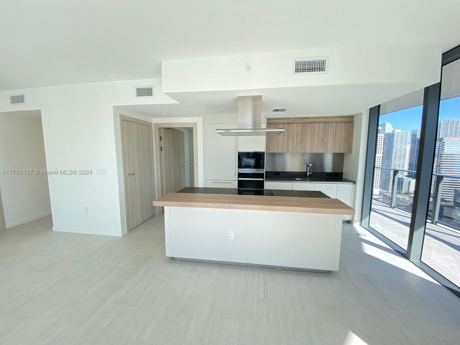 a living room with stainless steel appliances kitchen island granite countertop a refrigerator and a stove top oven