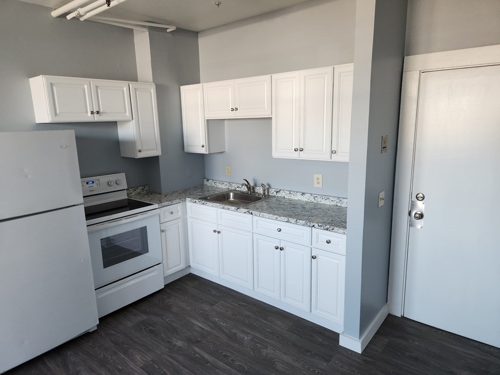 a kitchen with granite countertop white cabinets and white appliances