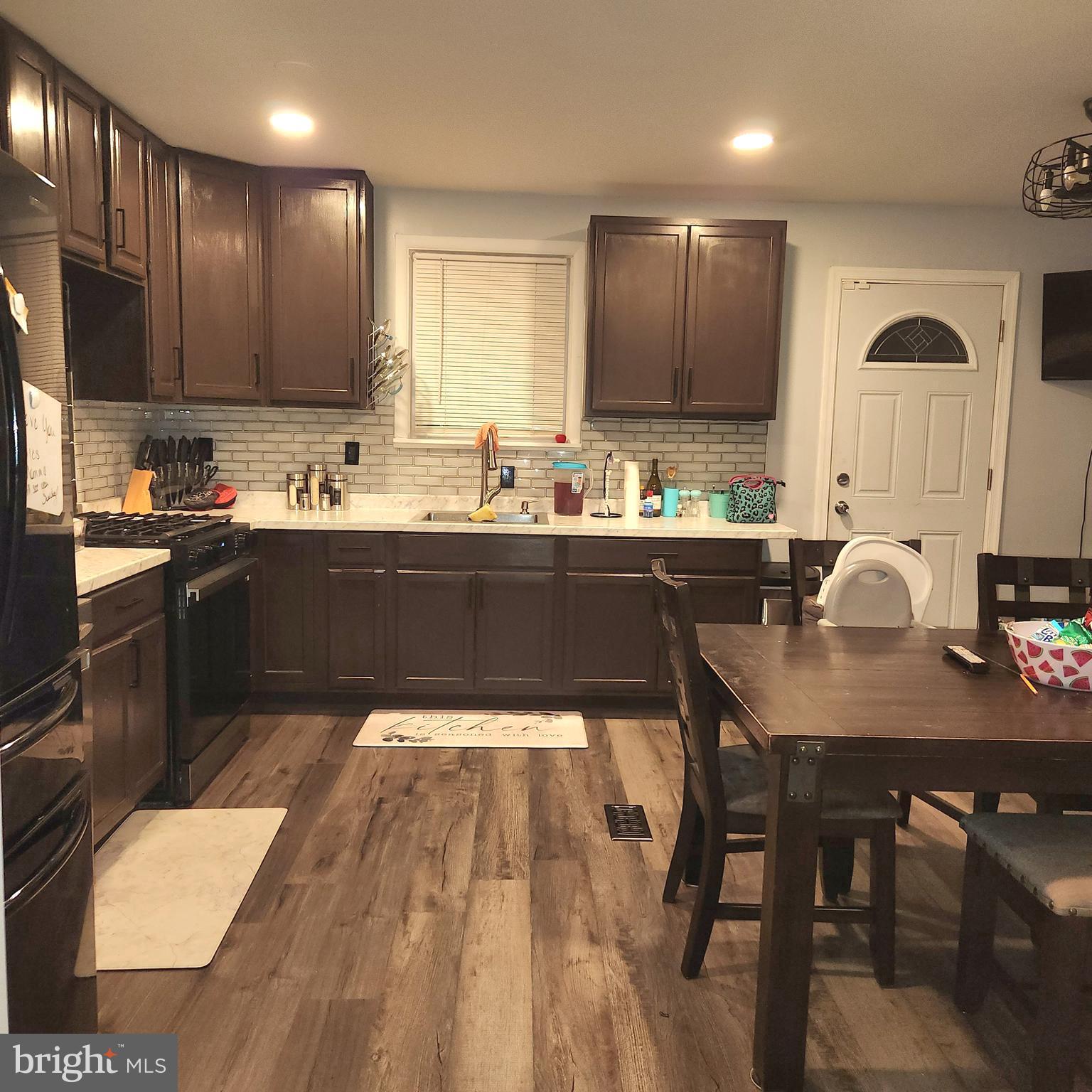 a kitchen with a sink a stove a refrigerator cabinets and dining table