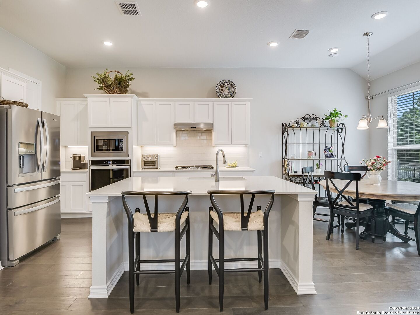 a dining room with stainless steel appliances a dining table chairs and refrigerator