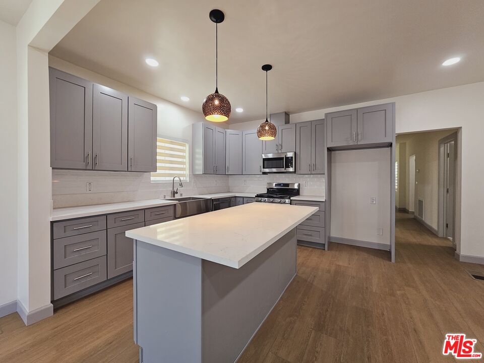 a kitchen with kitchen island a sink stainless steel appliances and wooden floor