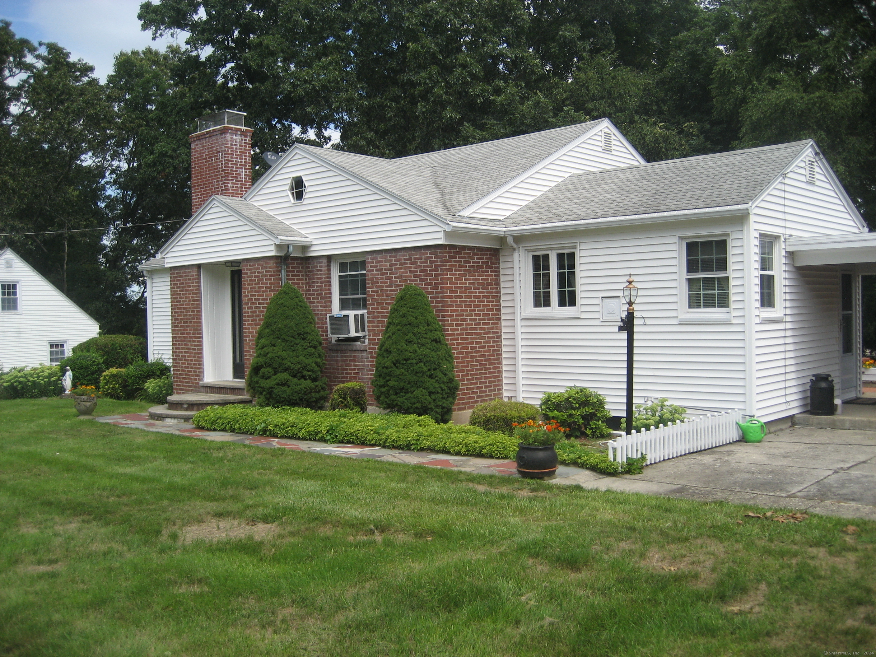 a view of a white house next to a yard and plants