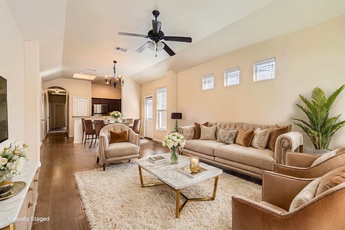 a living room with furniture kitchen view and a chandelier