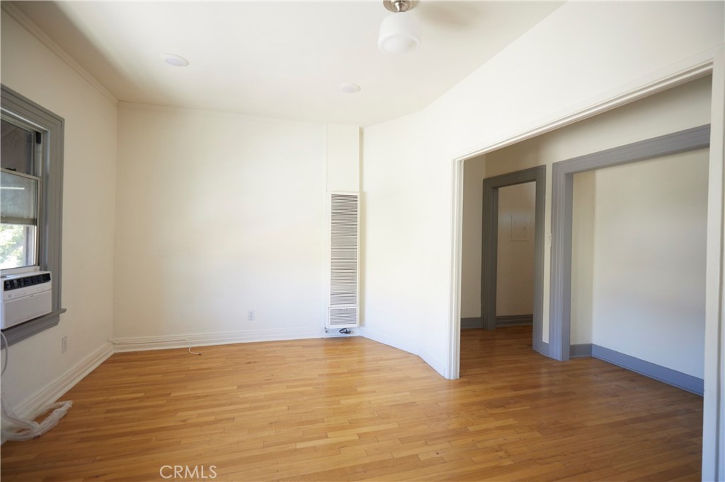 a view of an empty room with wooden floor and a window