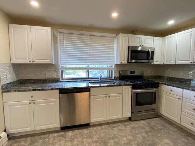 a kitchen with granite countertop white cabinets and stainless steel appliances