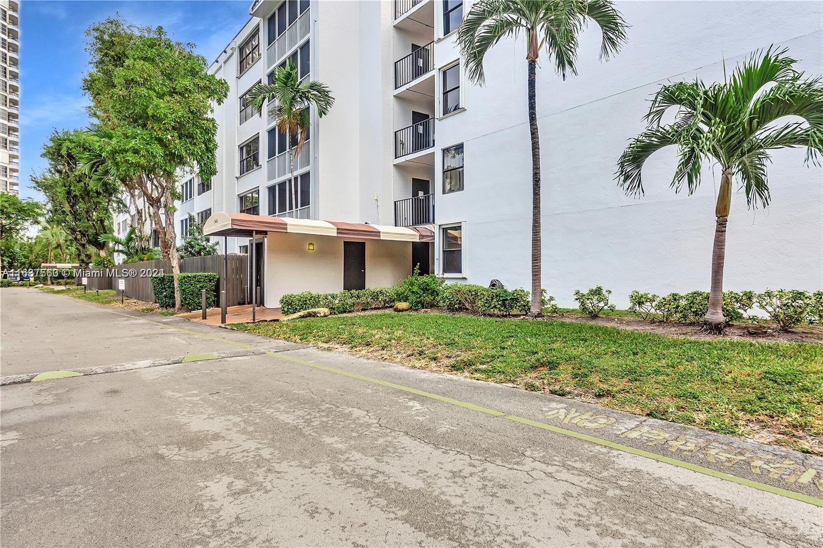 a front view of multi story residential apartment building with yard and green space