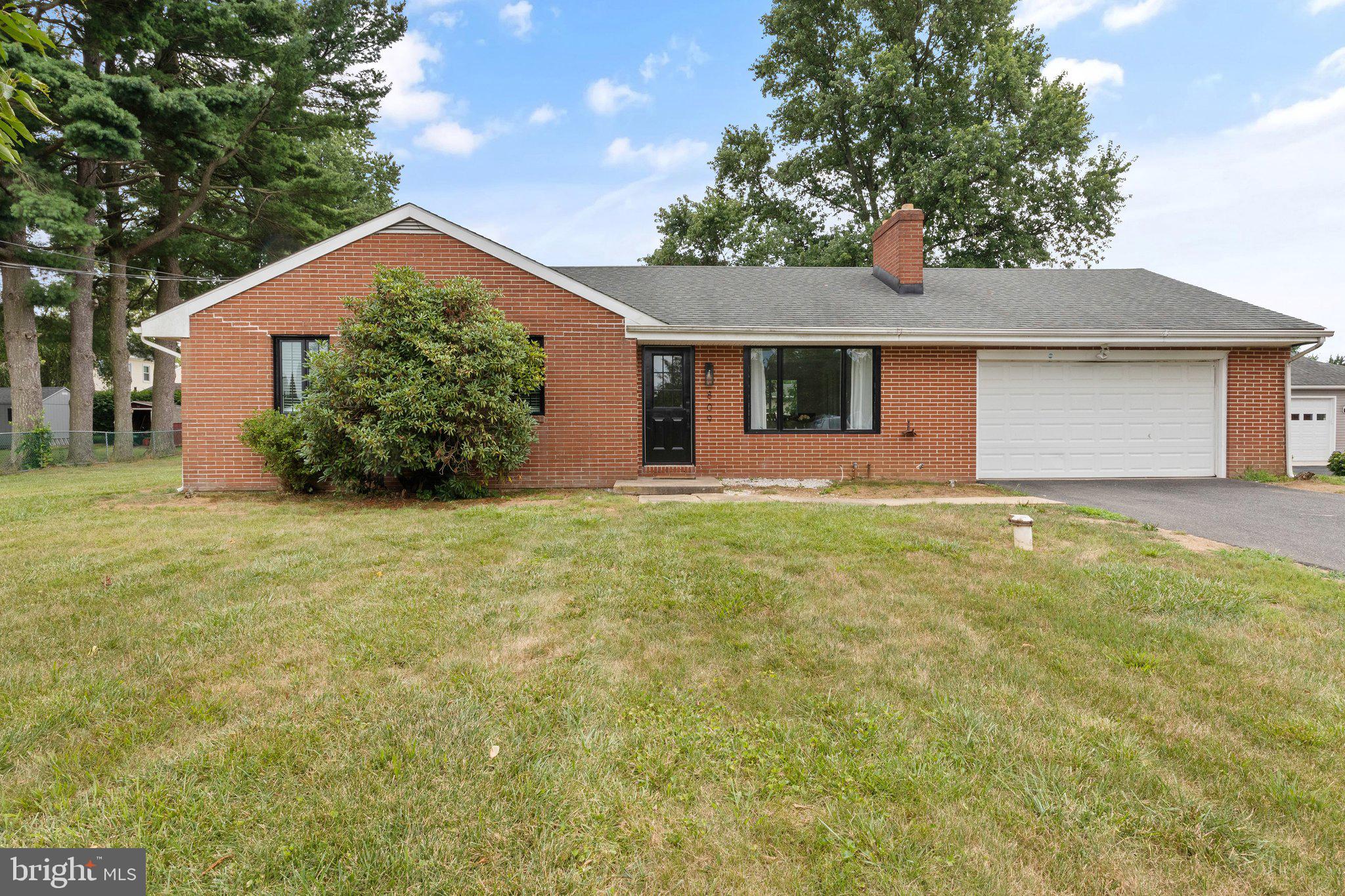 a front view of house with yard and trees in the background