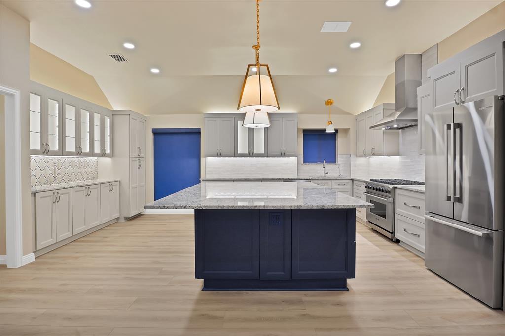 a kitchen with kitchen island a counter top space a sink stainless steel appliances and cabinets