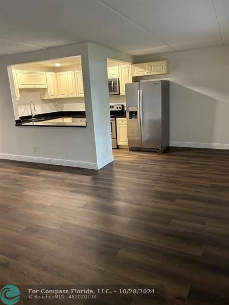 a view of a refrigerator in kitchen and an empty room