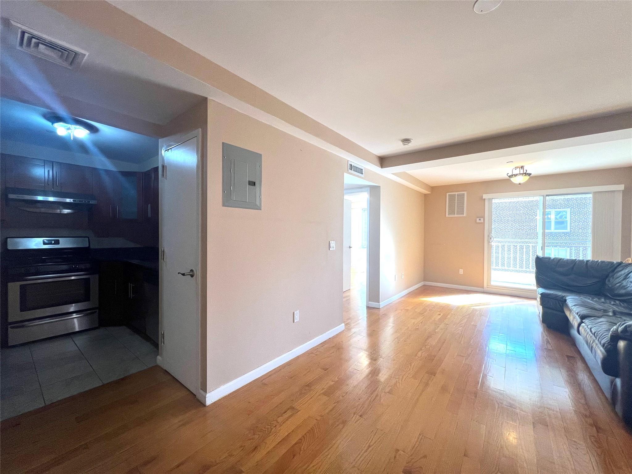 Living room with electric panel and light hardwood / wood-style flooring