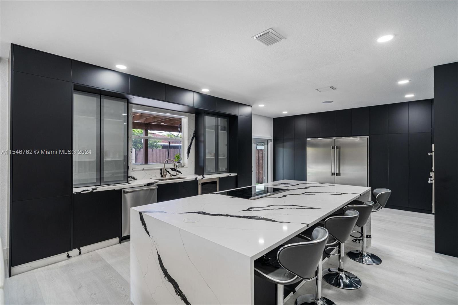 a dining hall with stainless steel appliances kitchen island a table and chairs