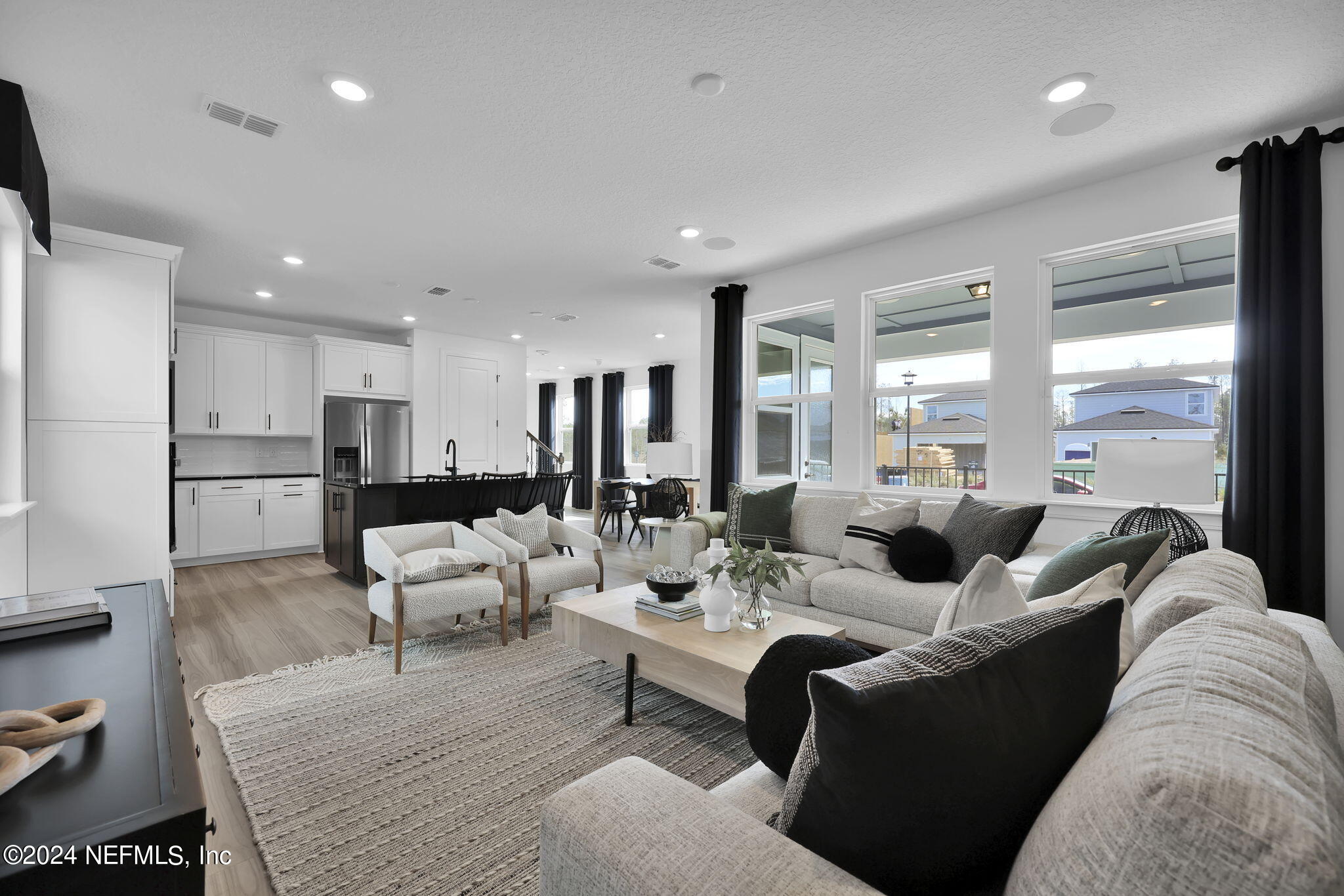 a living room with furniture kitchen view and a large window