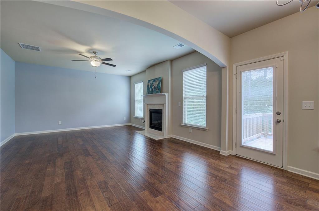 an empty room with wooden floor fireplace and windows