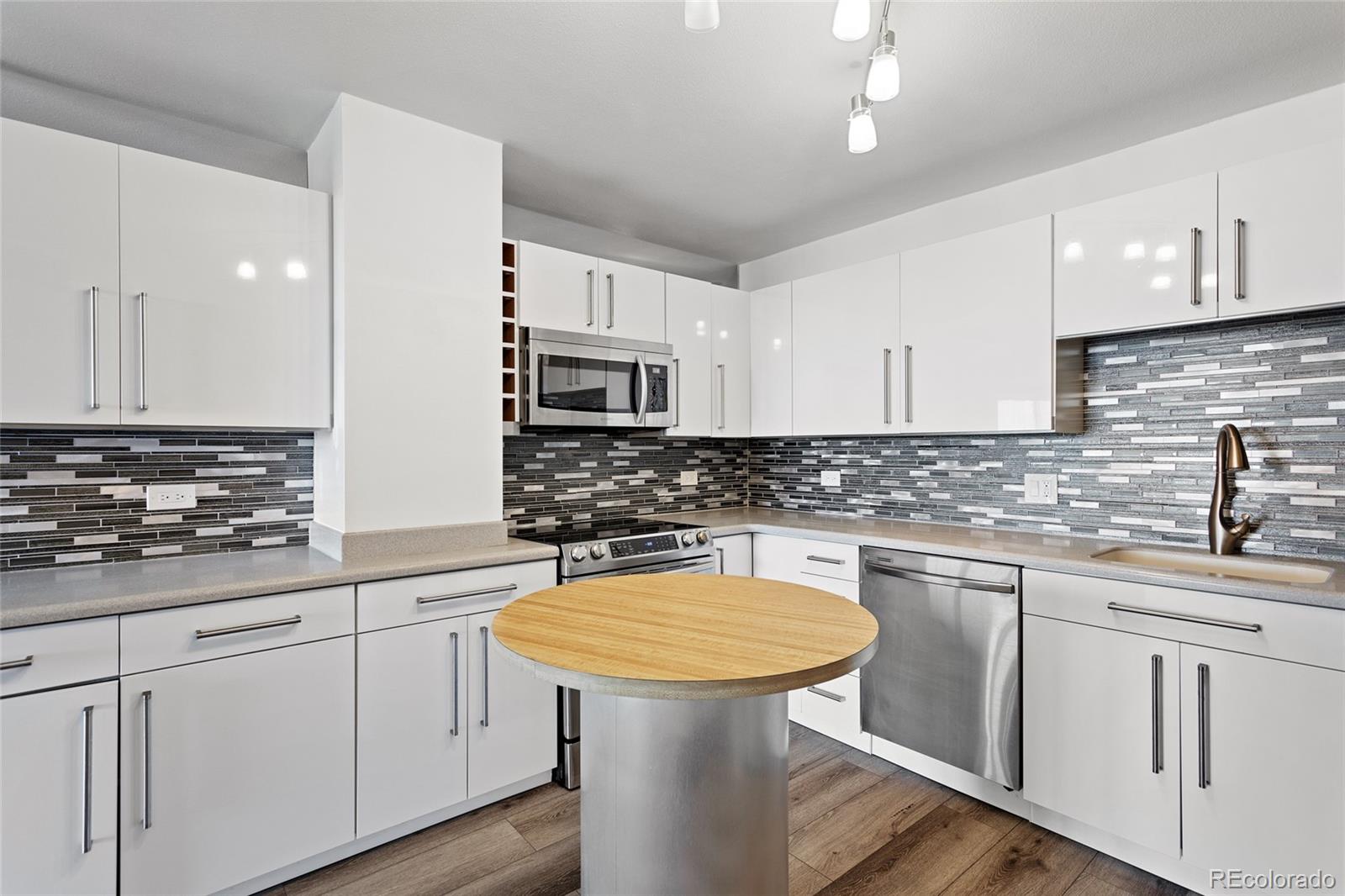 a kitchen with stainless steel appliances white cabinets sink and wooden floor