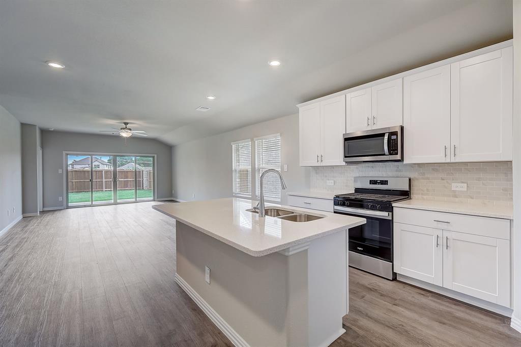 a kitchen with kitchen island granite countertop a sink cabinets and wooden floor