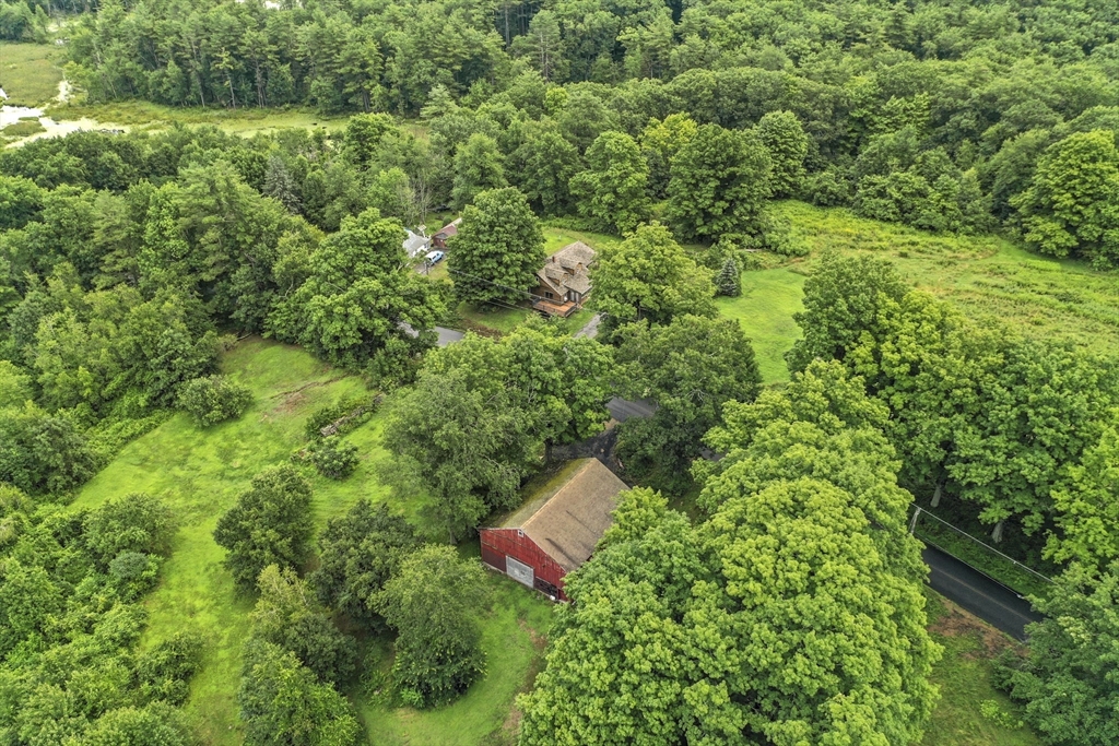 an aerial view of residential house with outdoor space and trees all around