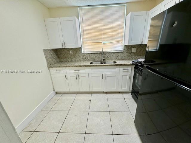 a kitchen with a sink a stove and black cabinets