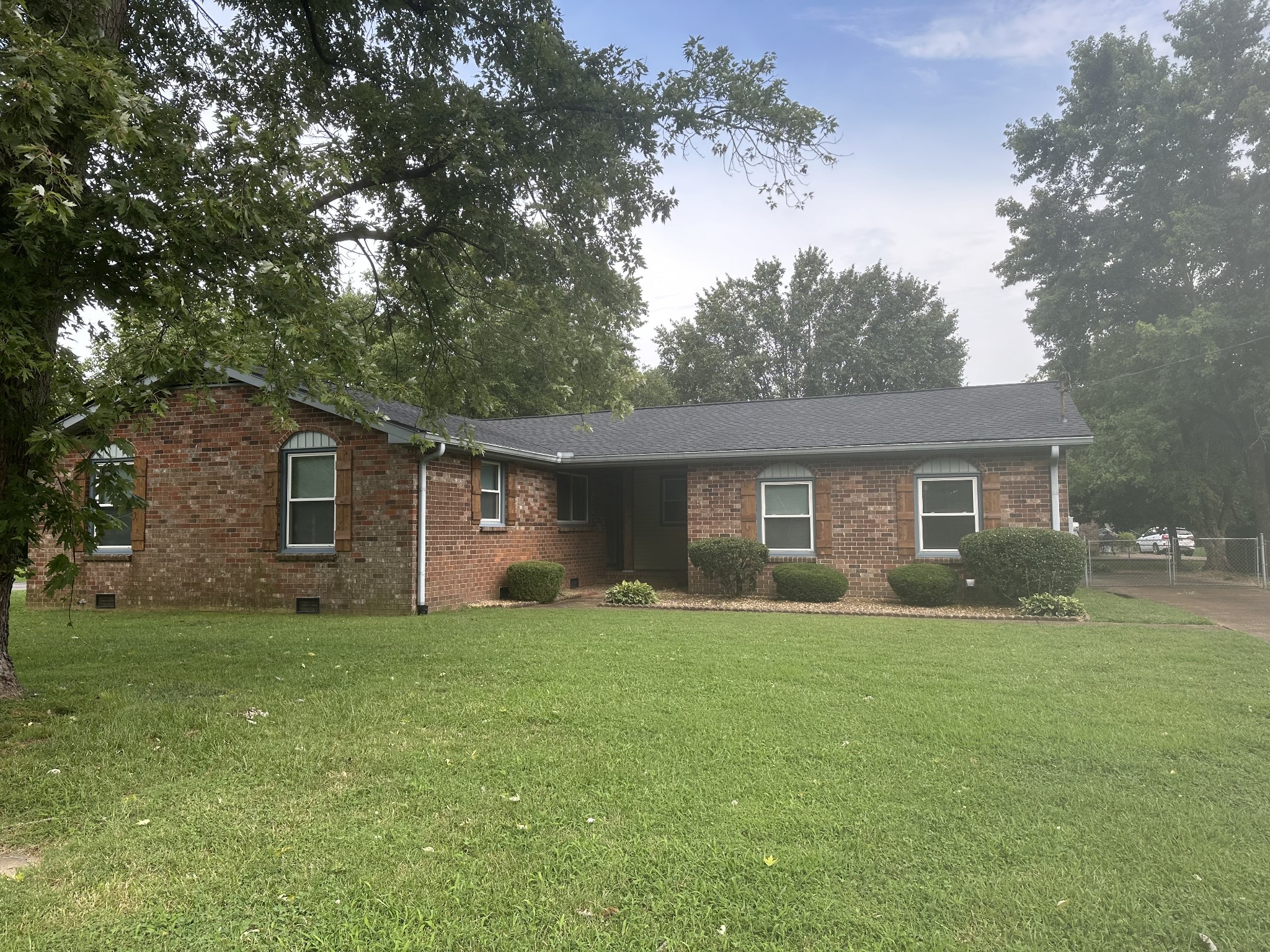 a brick house next to a yard with a large tree