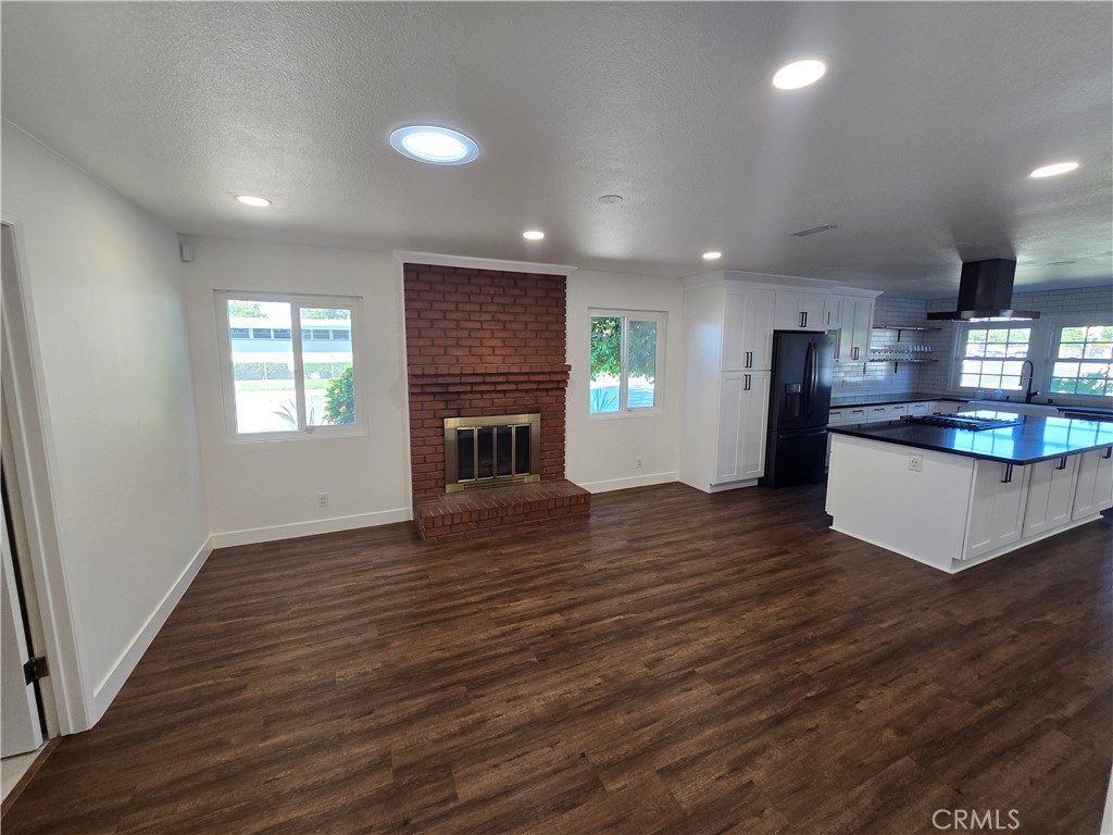 an empty room with wooden floor fireplace and windows