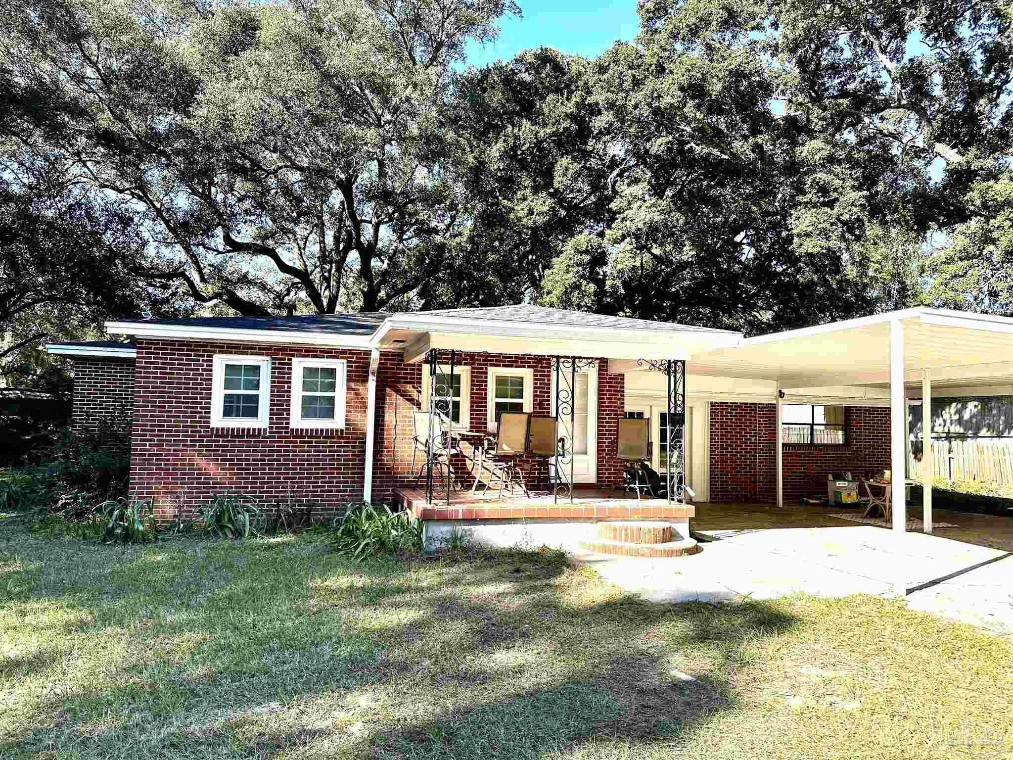 a front view of a house with a yard outdoor seating and covered with trees