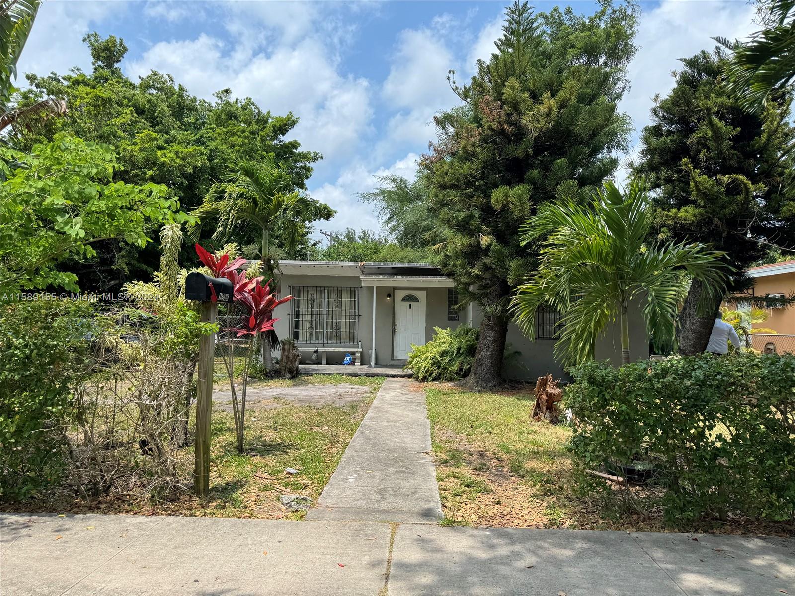 a front view of a house with a yard and potted plants