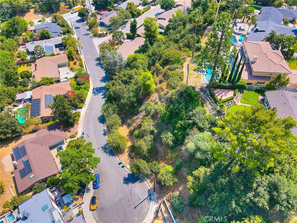 an aerial view of residential houses with outdoor space and trees all around