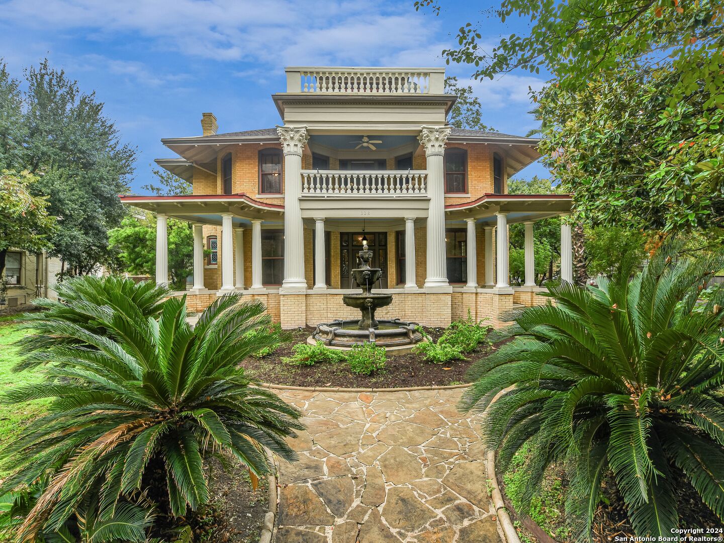 a view of a white house with a big yard and potted plants