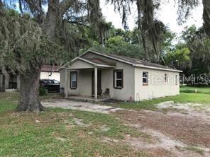 a view of a house with a yard and large tree