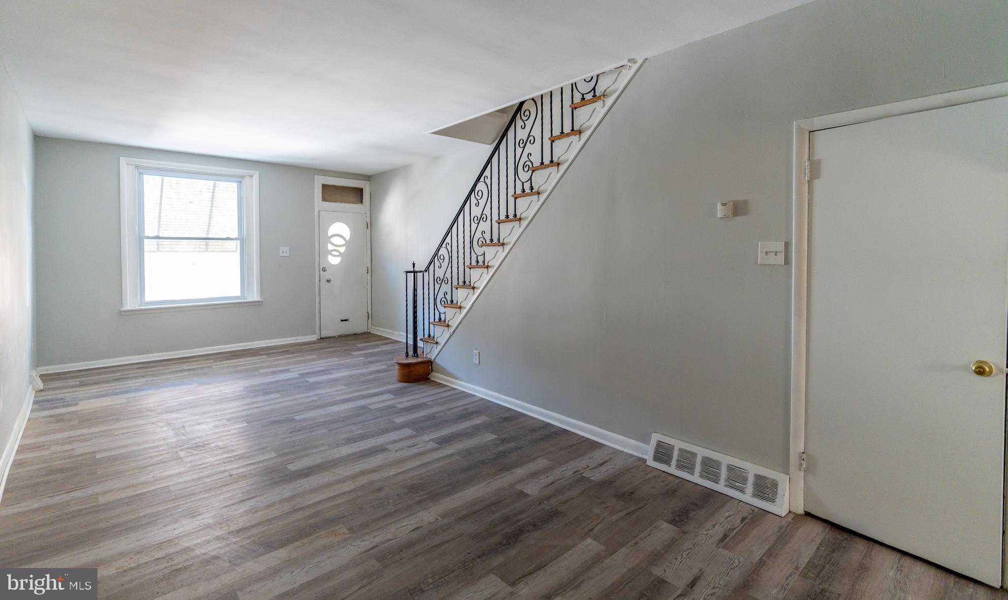 a view of an empty room with wooden floor and stairs