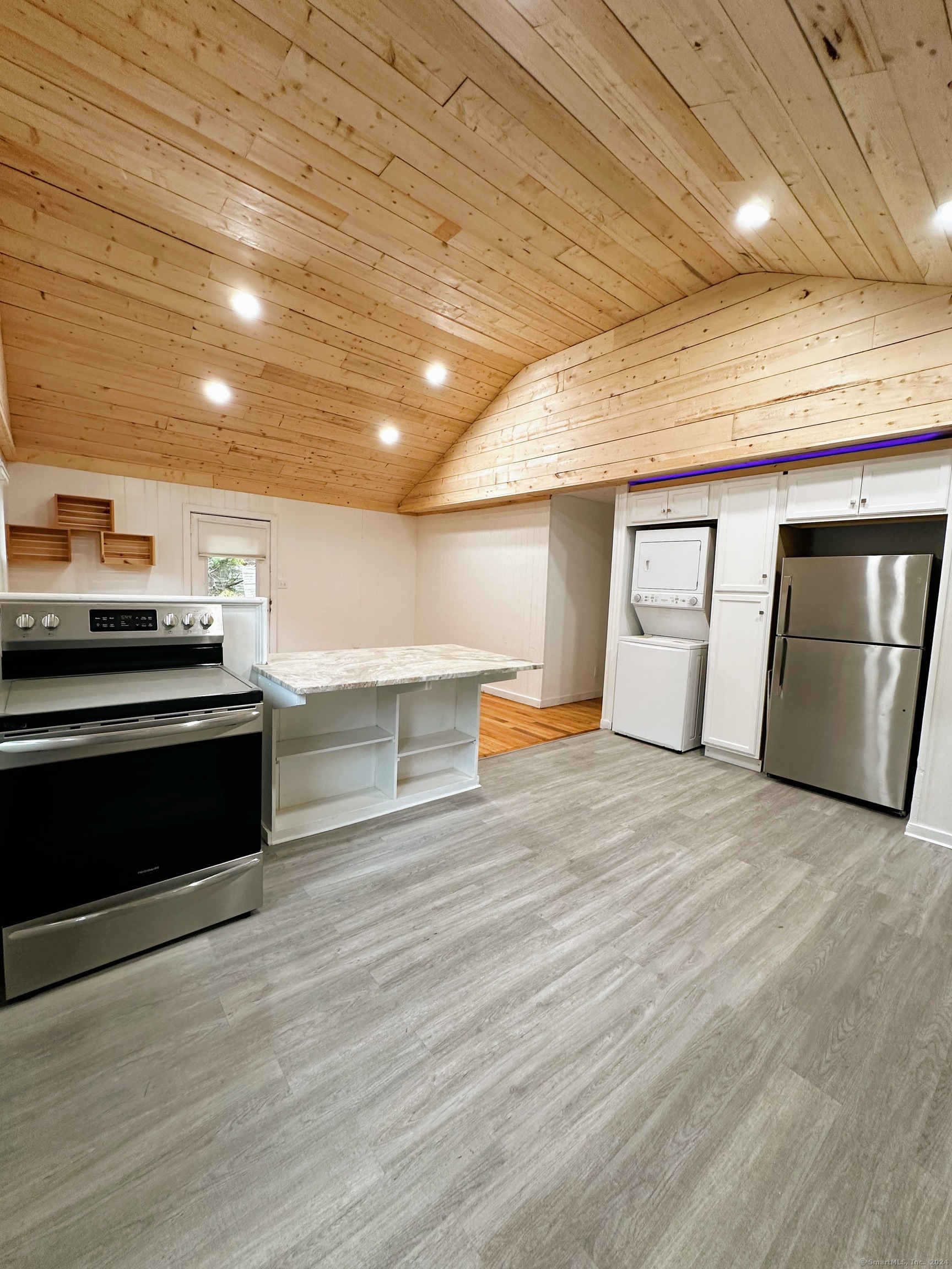 a view of an empty room with wooden floor and electronic appliances