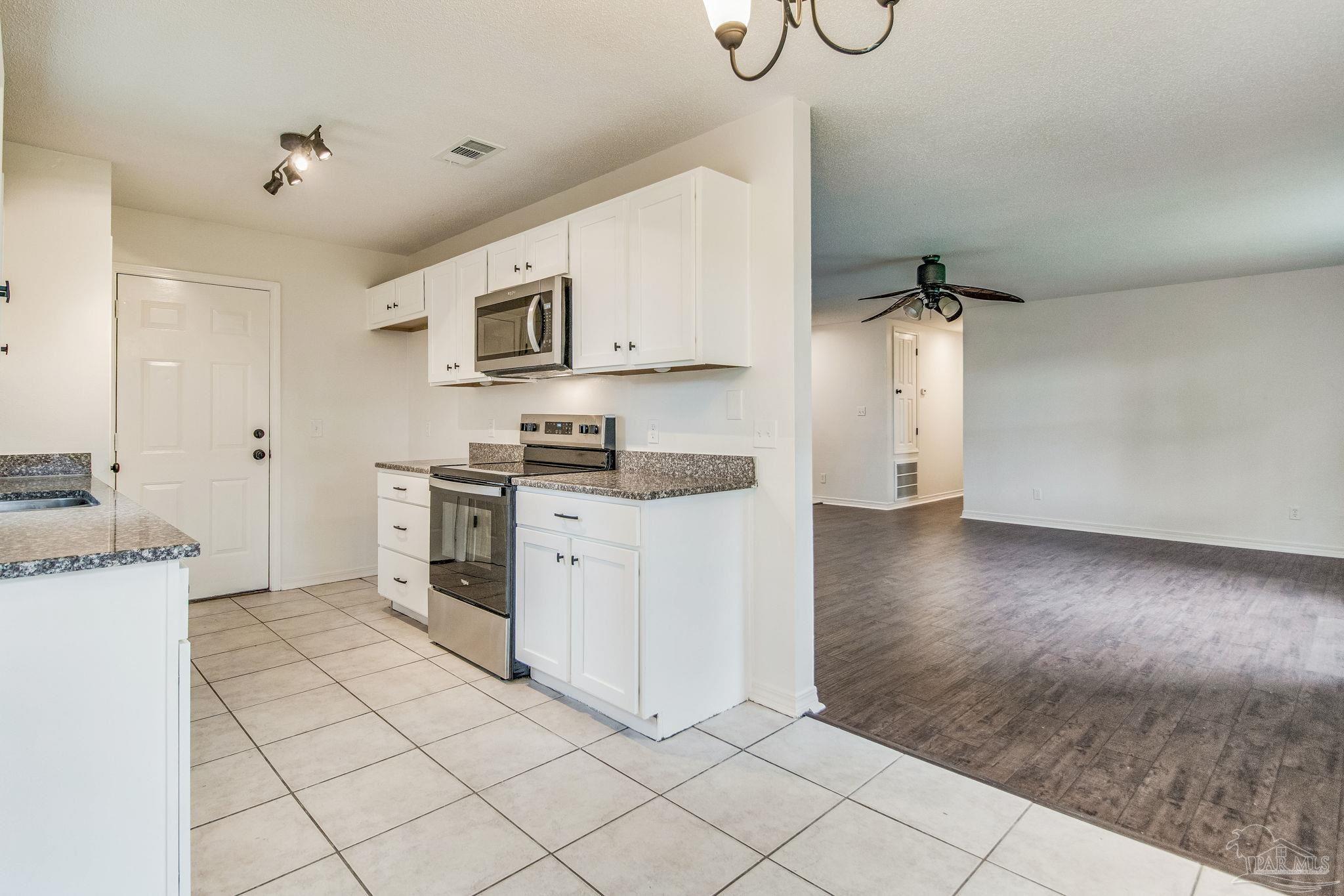 a kitchen with granite countertop white cabinets and stainless steel appliances