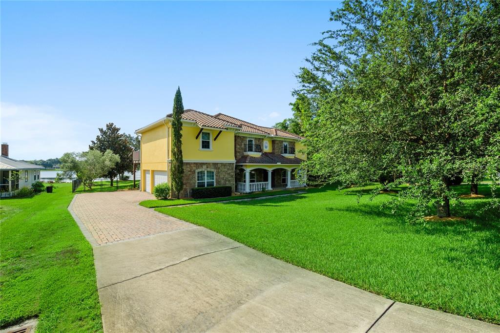 a view of a big house with a big yard and large trees