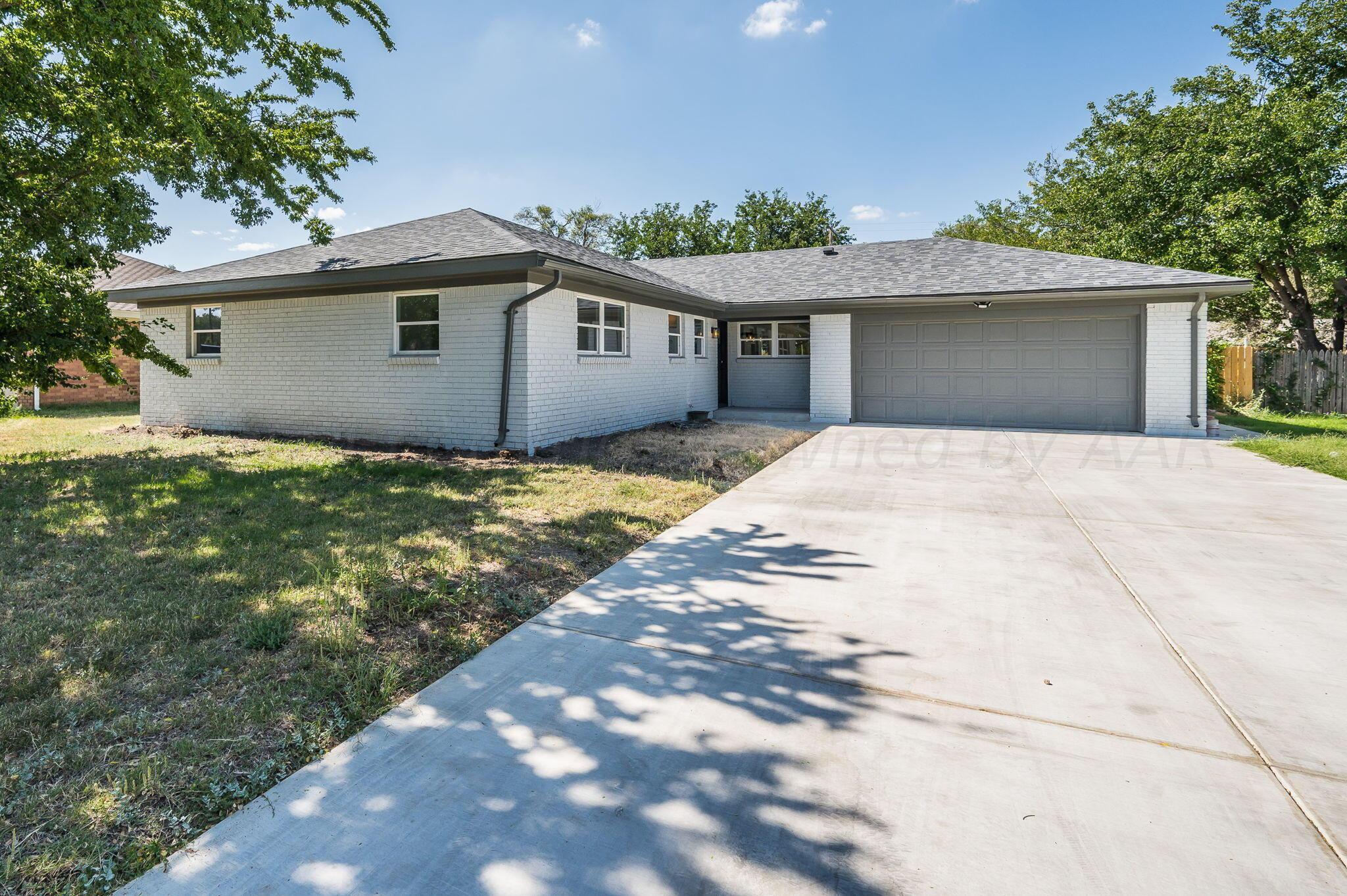 a front view of house with yard and trees in the background