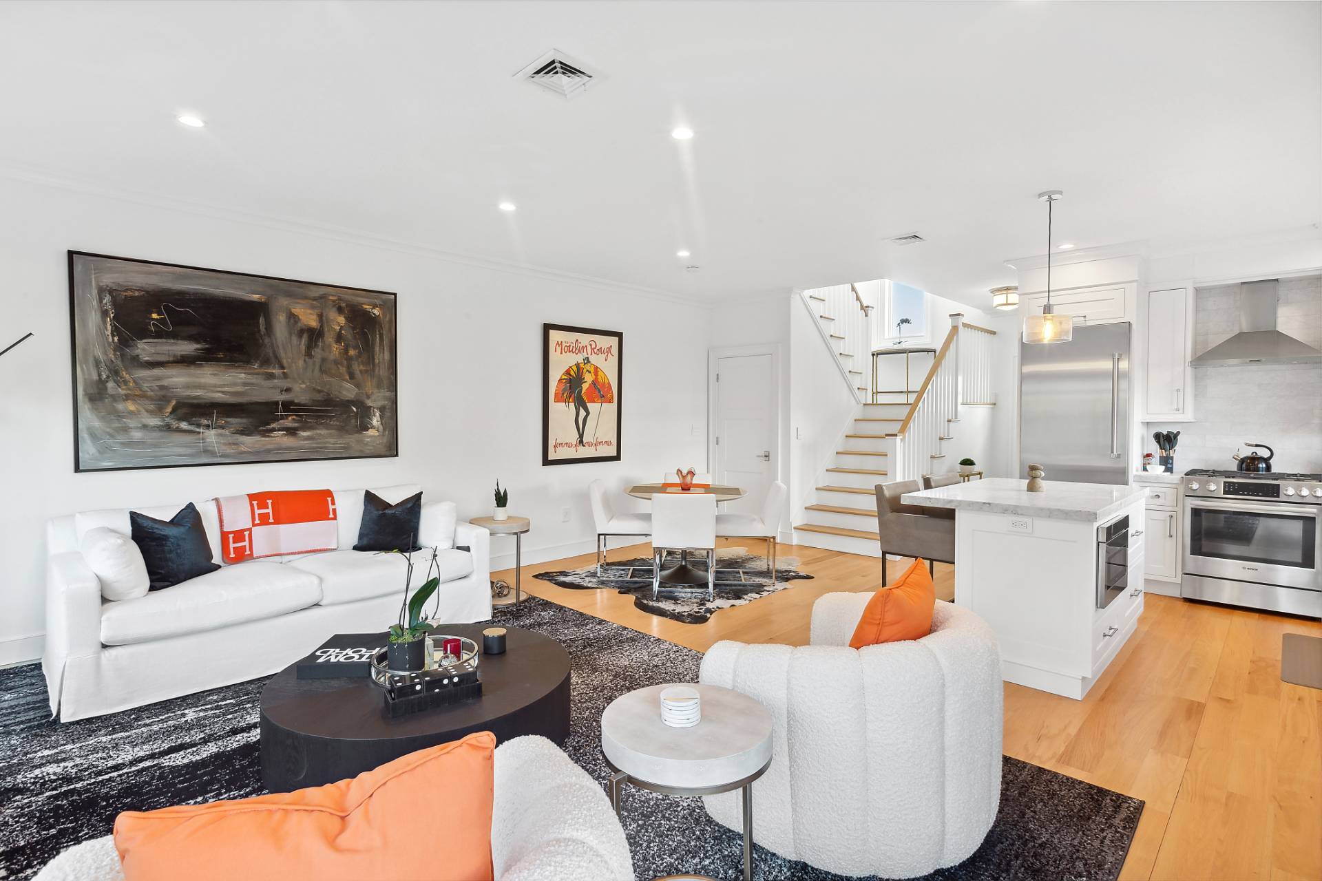 a living room with furniture kitchen view and a wooden floor